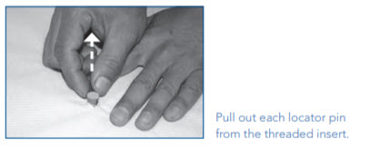 Hand pulling a locator pin from the threaded insert.