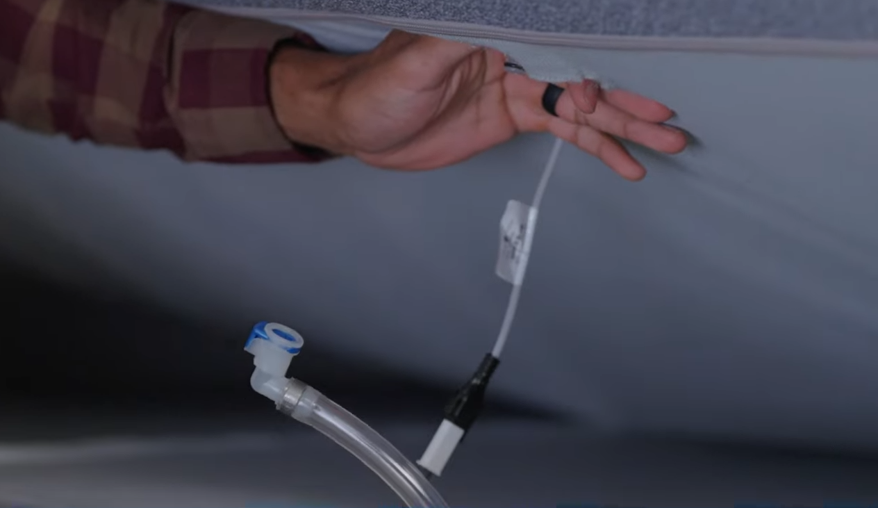 Air hose disconnected from the air chamber with a hand holding up the underside of the mattress.