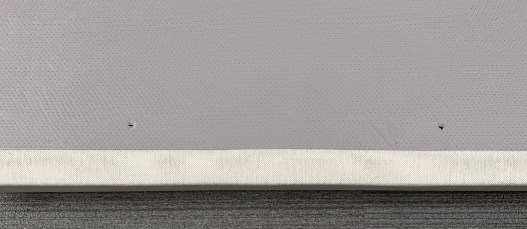A view of the two retainer bar holes after the cover of the base has been pierced.
