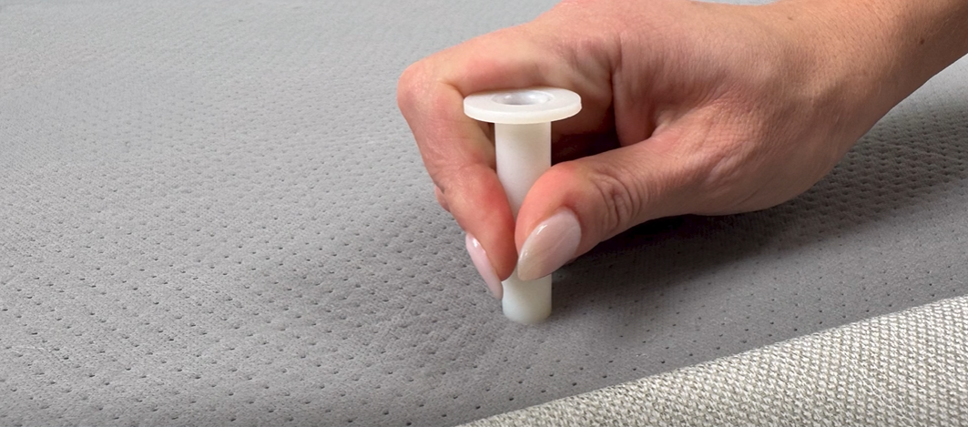 A close-up of a hand pushing in a locater pin into the retainer bar holes.